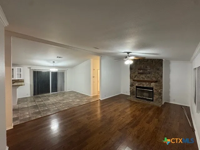 an empty room with wooden floor fireplace and windows