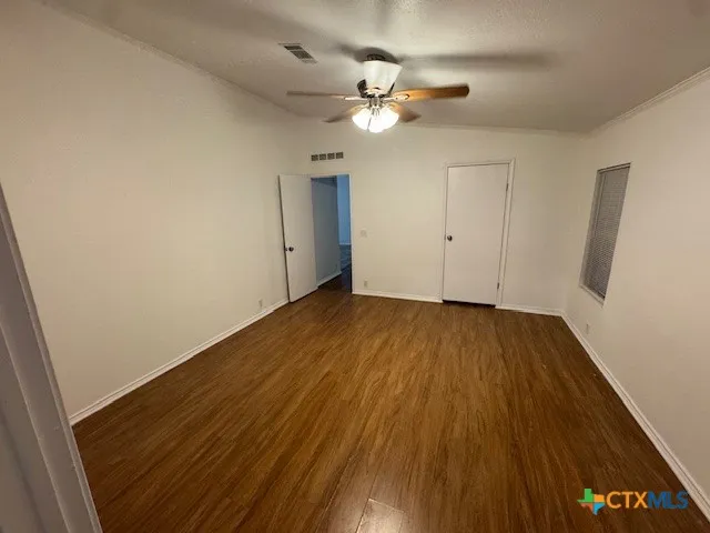 a view of a room with wooden floor and a ceiling fan