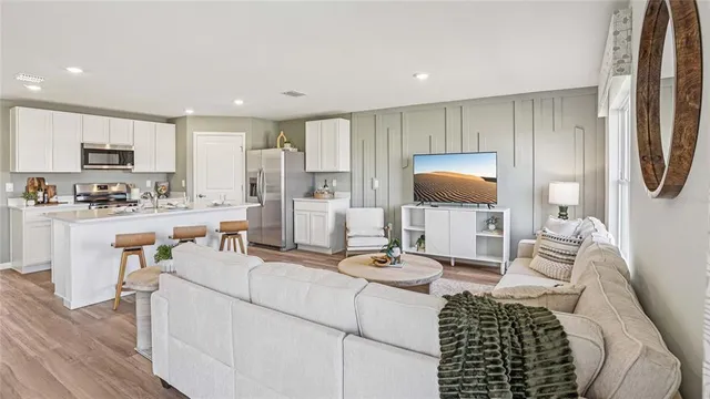 a living room with furniture a flat screen tv and kitchen view