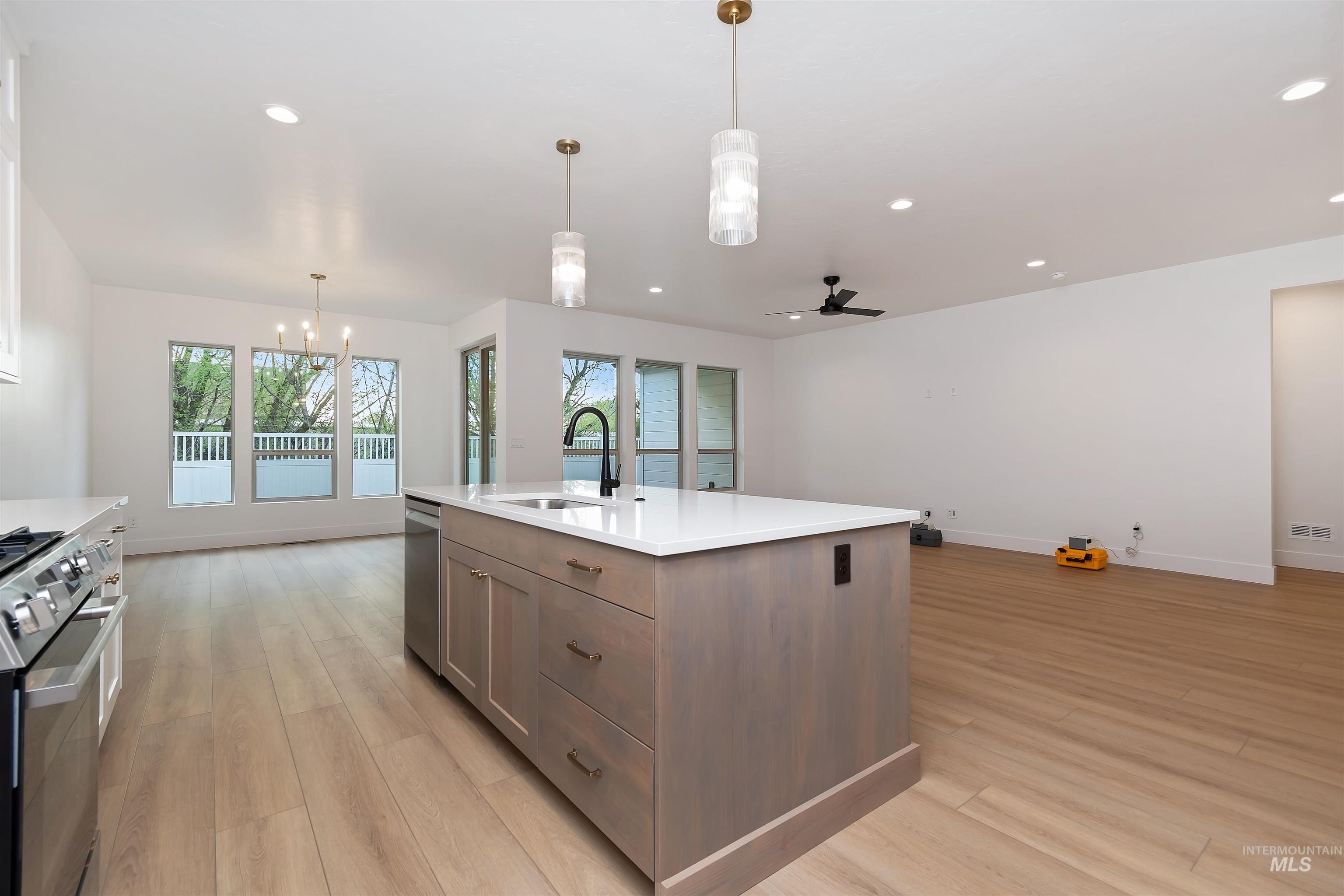 4302 Tropic Way Caldwell, ID 83607 - Photo 6 of 32 Kitchen with light wood-style floors, stainless steel appliances, an island with sink, and a ceiling fan