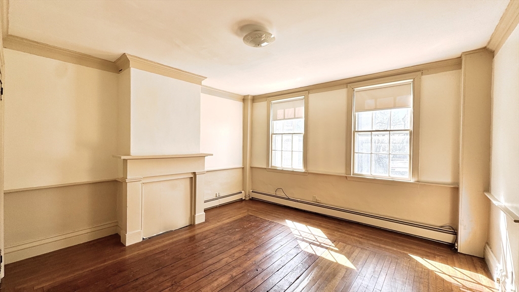 18 State Street, Unit 1 Marblehead, MA 01945 - Photo 7 of 16 an empty room with wooden floor and windows