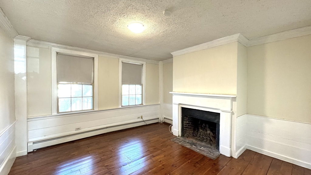 18 State Street, Unit 1 Marblehead, MA 01945 - Photo 10 of 16 an empty room with wooden floor fireplace and windows