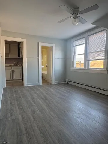 a view of empty room with wooden floor and fan