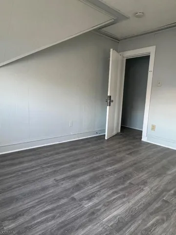 a view of an empty room with wooden floor and closet