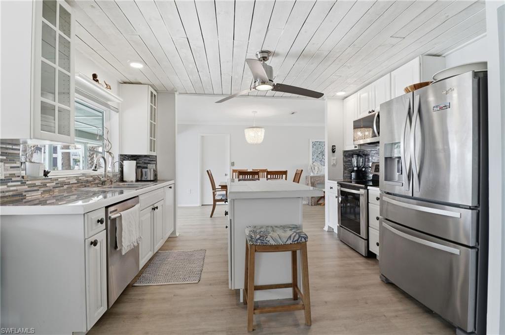 2211 Bayview Road Punta Gorda, FL 33950 - Photo 21 of 37 Kitchen with stainless steel appliances, wooden ceiling, white cabinets, decorative backsplash, and hanging light fixtures