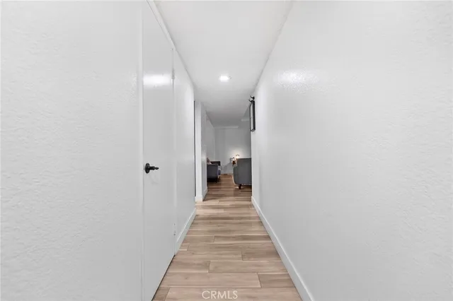 a view of a hallway with wooden floor and a bathroom