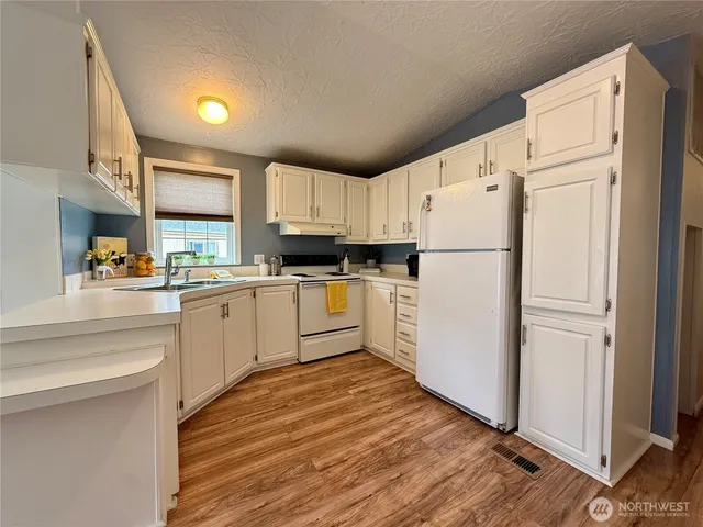 a kitchen with white cabinets and white appliances