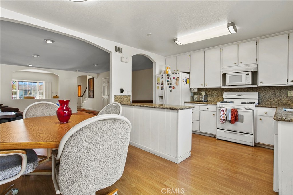4801 Redbluff Circle Irvine, CA 92604 - Photo 10 of 34 a living room with stainless steel appliances furniture a kitchen island wooden floors and white walls
