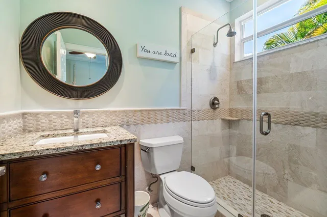 a bathroom with a granite countertop sink a toilet and shower