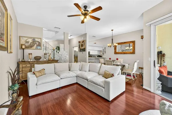 a living room with furniture kitchen view and a wooden floor