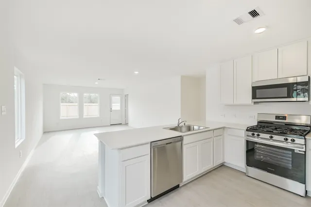 a kitchen with stainless steel appliances granite countertop white cabinets and a stove a oven with white countertops