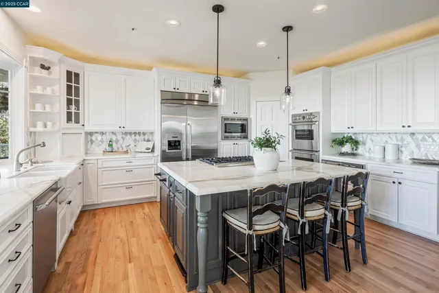 a kitchen with stainless steel appliances kitchen island granite countertop a table chairs sink and cabinets