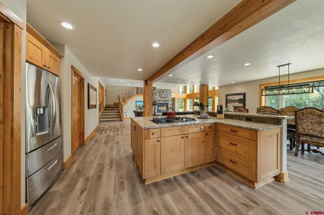 a kitchen with stainless steel appliances granite countertop a refrigerator a sink dishwasher a stove and white countertops with wooden floor