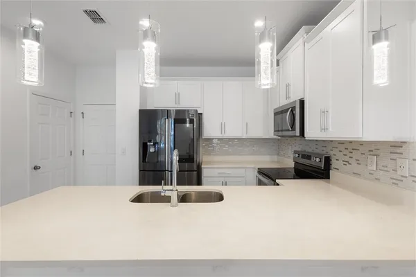 a kitchen with stainless steel appliances kitchen island granite countertop a refrigerator and a sink