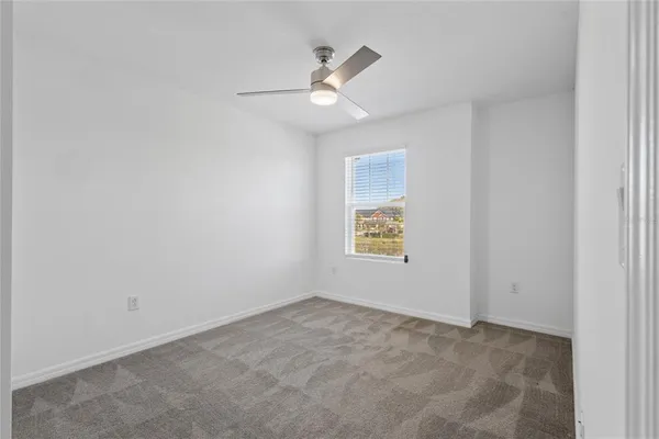 an empty room with a window and ceiling fan