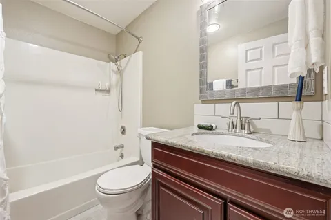 a bathroom with a granite countertop toilet sink and mirror