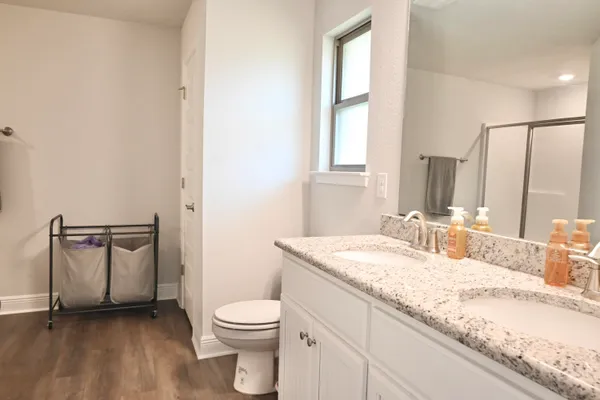a bathroom with a granite countertop sink toilet and mirror