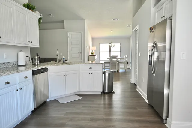 a kitchen with cabinets stainless steel appliances and wooden floor