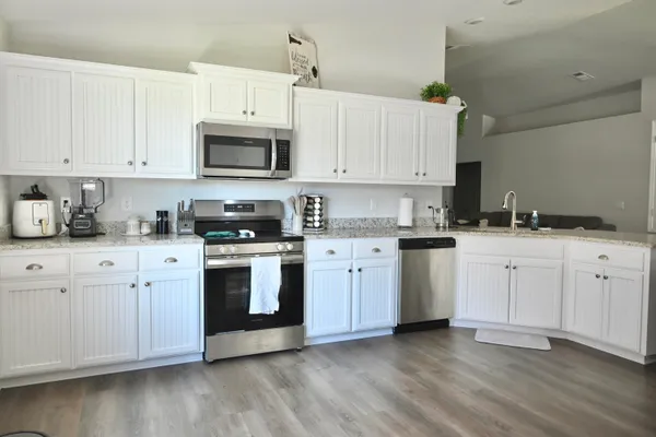 a kitchen with cabinets stainless steel appliances and wooden floor