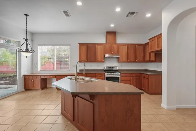 a large kitchen with granite countertop a stove sink and cabinets
