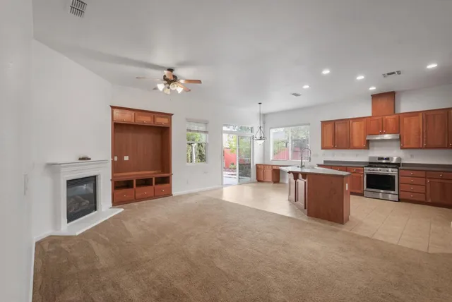 a kitchen with stainless steel appliances granite countertop a stove a sink a refrigerator and a fireplace