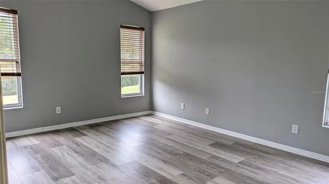 an empty room with wooden floor and windows
