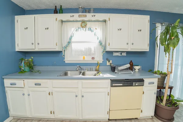 a kitchen with granite countertop white cabinets white appliances and a sink