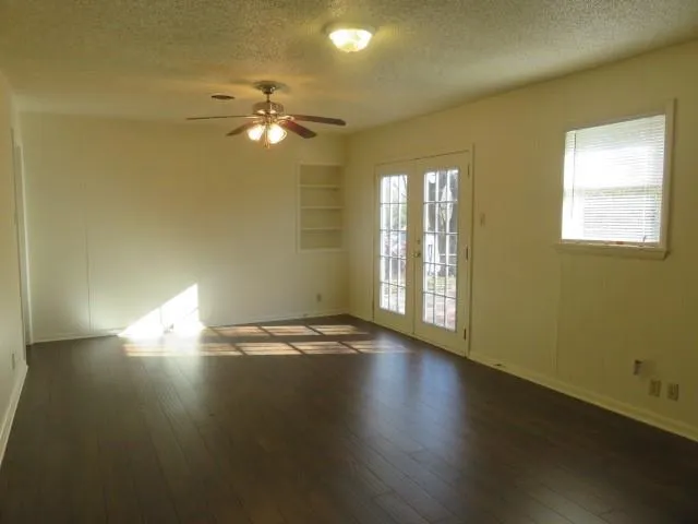 a view of empty room with wooden floor and fan
