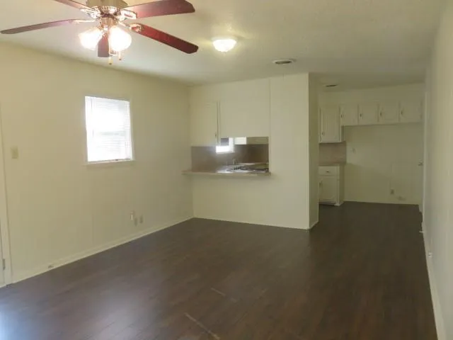 an empty room with a chandelier fan and windows