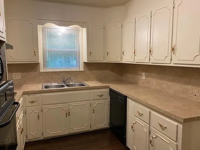 a kitchen with granite countertop white cabinets and sink
