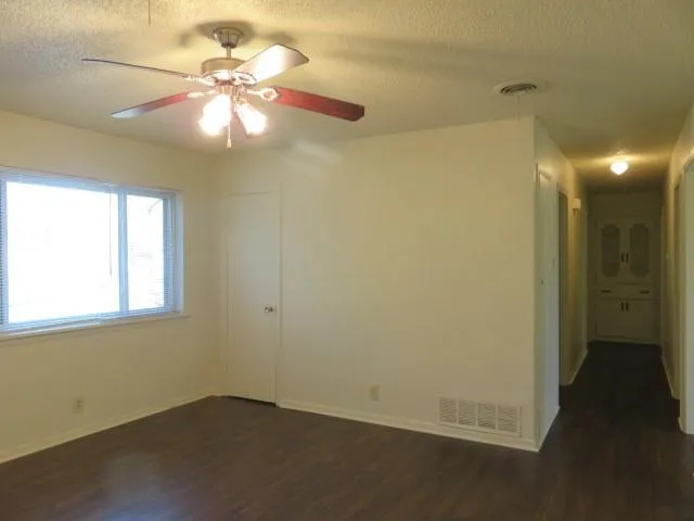 an empty room with windows and fan