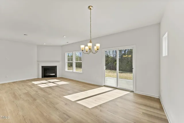a view of an empty room with window and chandelier fan