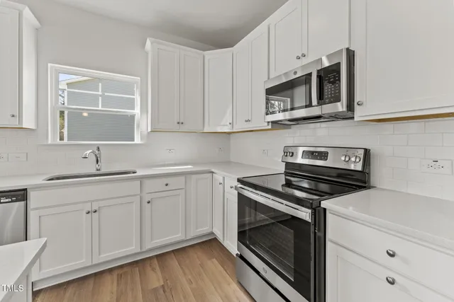 a kitchen with white cabinets stainless steel appliances and sink