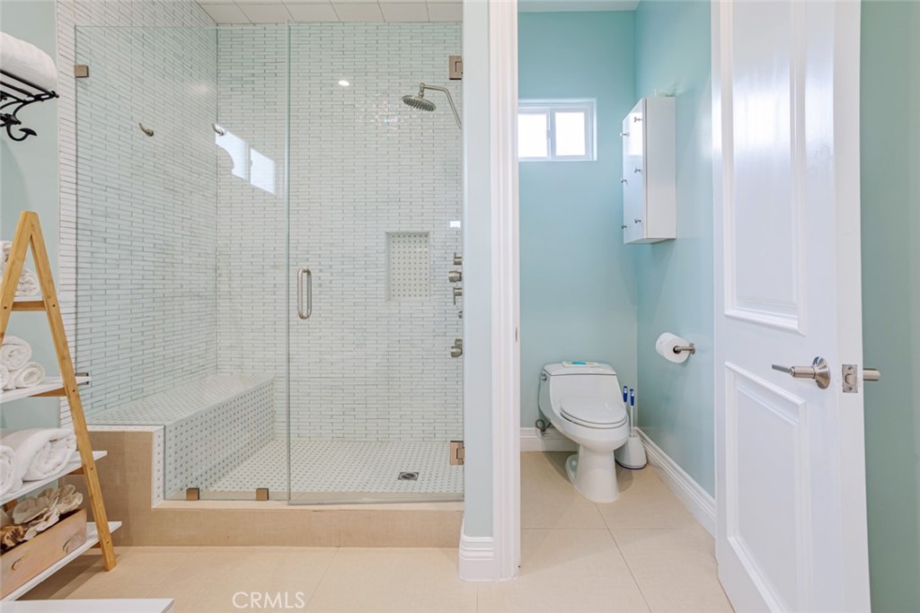 12945 Calvert Street Van Nuys, CA 91401 - Photo 21 of 57 a bathroom with a granite countertop mirror a toilet and a shower