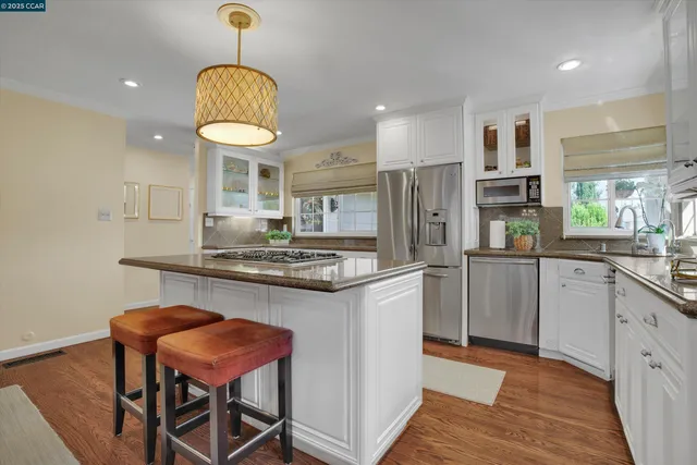 a kitchen with stainless steel appliances granite countertop a sink a stove refrigerator and cabinets