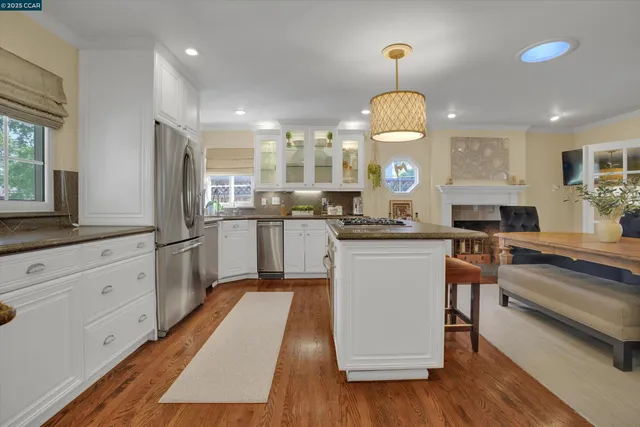 a kitchen with a refrigerator a stove a sink and a dining table with wooden floor