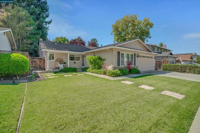 a view of a house with a big yard potted plants and large tree