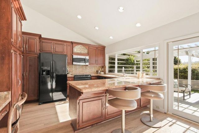 a kitchen with stainless steel appliances granite countertop a stove refrigerator and cabinets