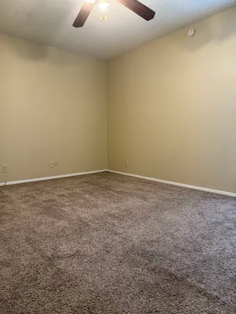 an empty room with a ceiling fan and carpet