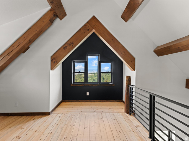 1225 Old Oregon Road Soda Springs, ID 83276 - Photo 34 of 67 Vaulted attic space featuring exposed wood beams, natural wood-finish flooring, a black accent wall, and a custom window array