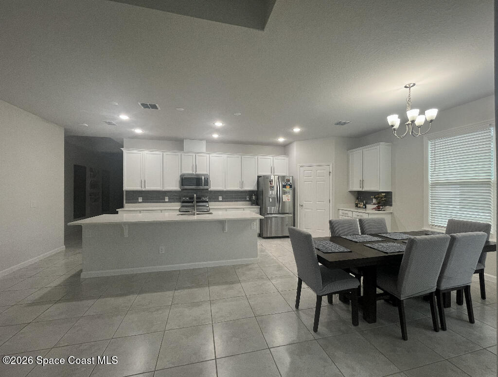 2359 Bonnyton Lane Palm Bay, FL 32907 - Photo 4 of 15 a kitchen with a dining table chairs stainless steel appliances and cabinets