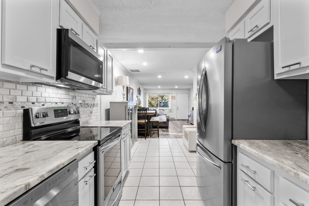 3 Dailey Street, Unit B Attleboro, MA 02703 - Photo 12 of 30 a kitchen with stainless steel appliances kitchen island granite countertop a refrigerator oven a sink dishwasher and white cabinets with wooden floor