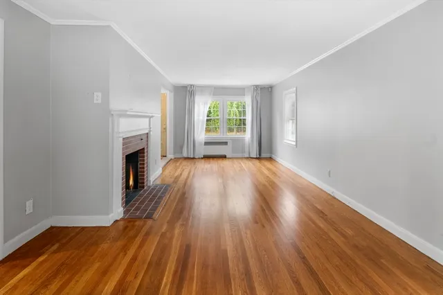 a view of empty room with wooden floor and fireplace