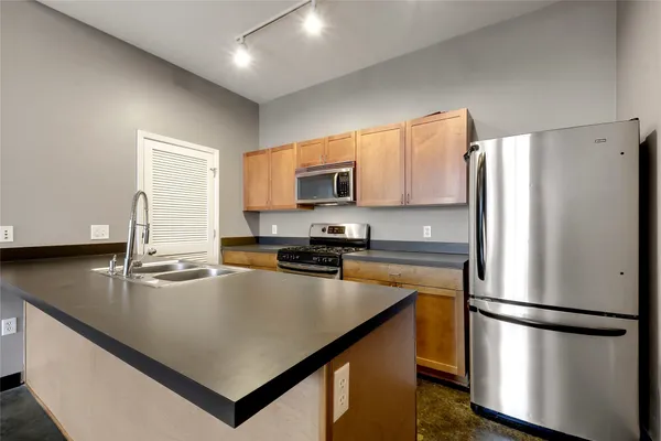 a kitchen with stainless steel appliances granite countertop a sink a stove and a refrigerator