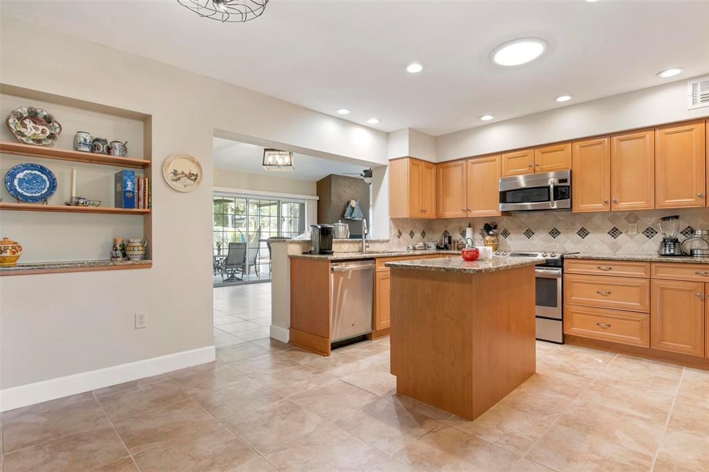 104 Alba Street West Venice, FL 34285 - Photo 13 of 42 a kitchen with kitchen island granite countertop wooden cabinets and white appliances