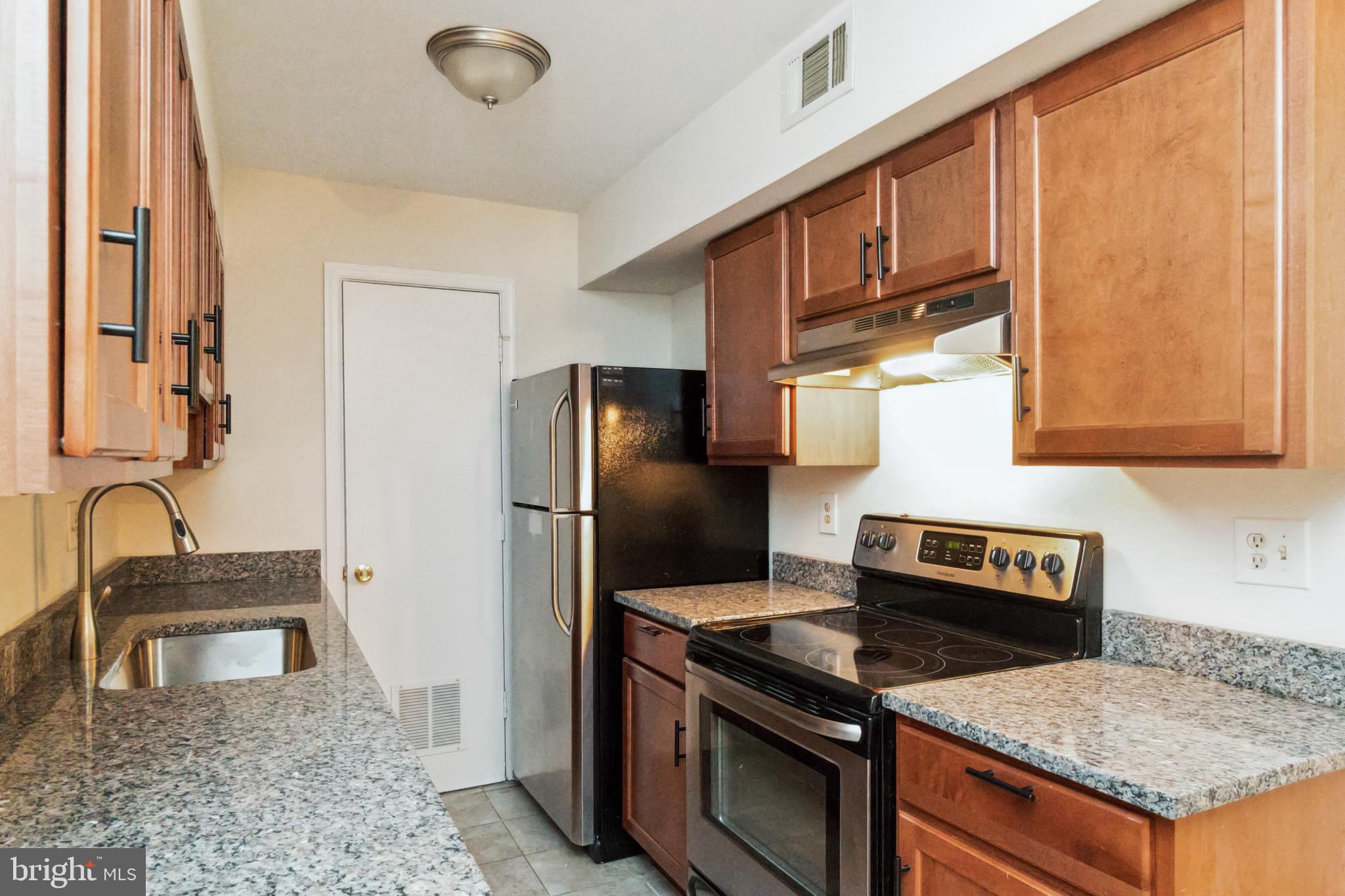 8312 Kingsgate Road, Unit 534 Springfield, VA 22152 - Photo 16 of 32 a kitchen with granite countertop a sink stove and refrigerator