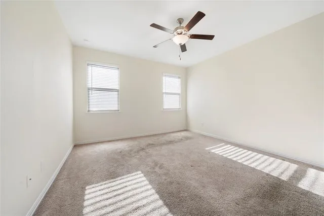 an empty room with windows and ceiling fan