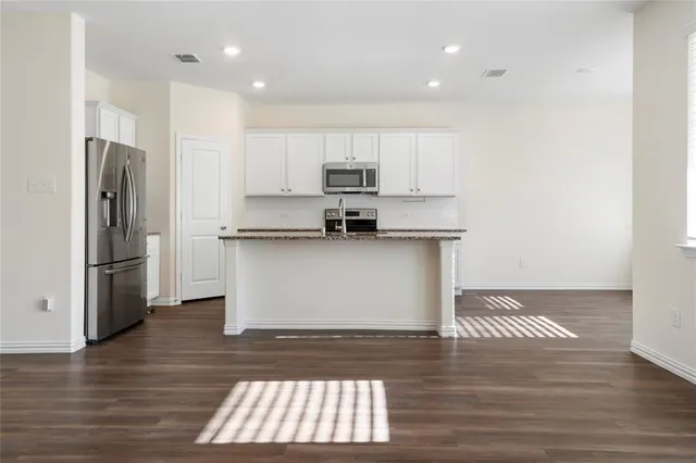 a kitchen with a refrigerator and white cabinets