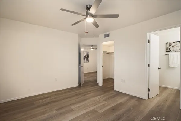 an empty room with wooden floor and ceiling fan