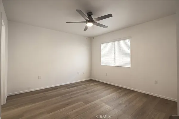 an empty room with wooden floor ceiling fan and windows